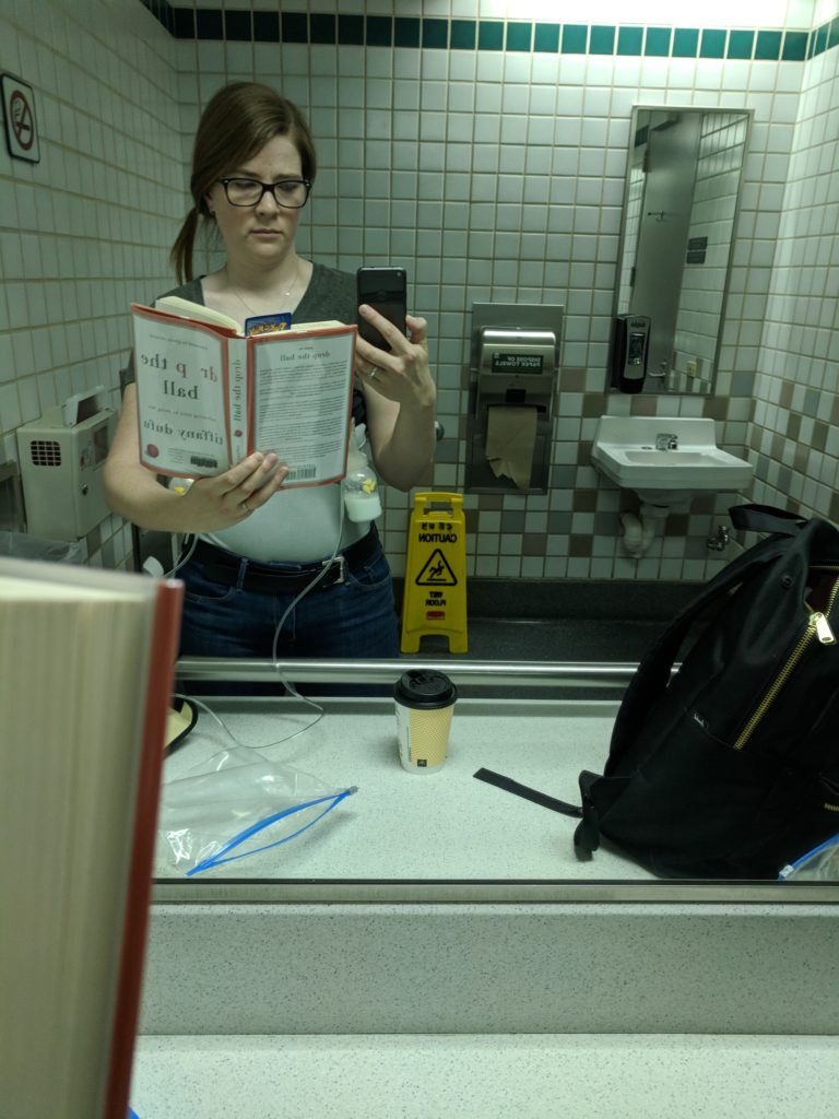 Kelly in a bathroom, pumping, reading "Drop the ball"