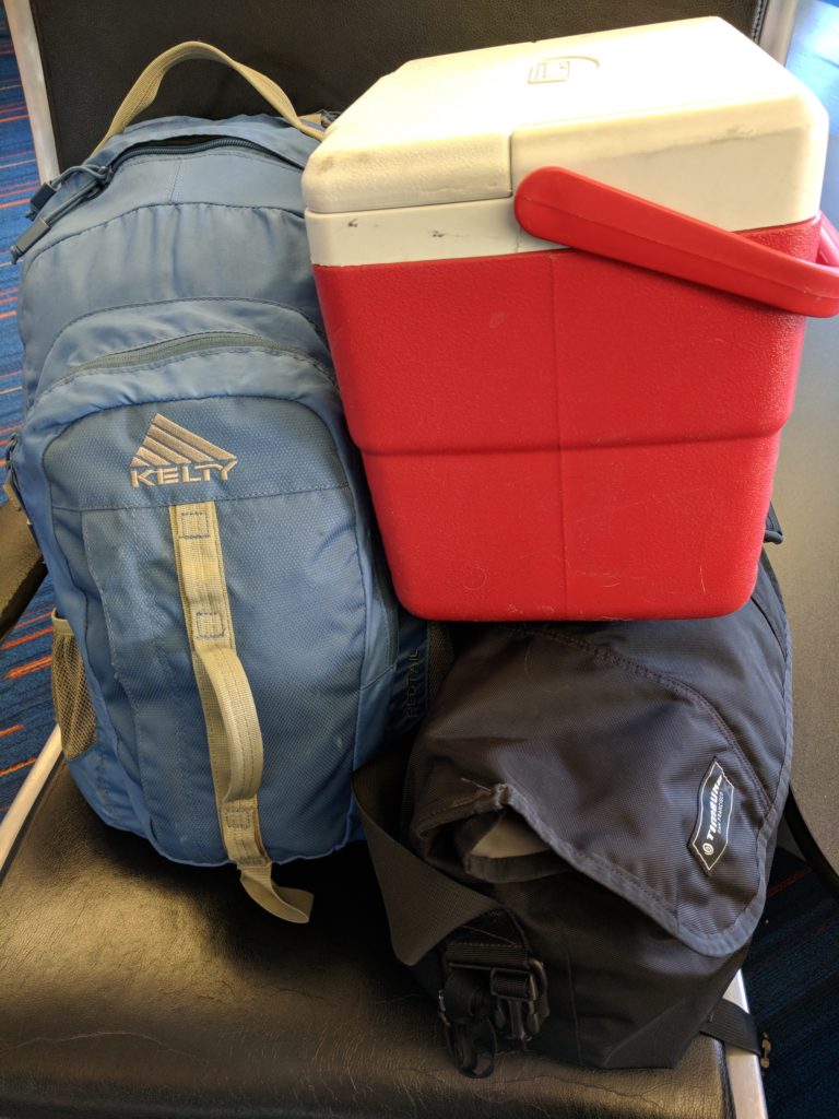 Blue backpack, black courier bag, small red cooler